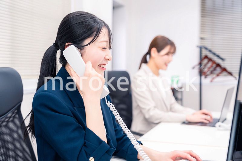 オフィスでにこやかに電話対応をするビジネスウーマン