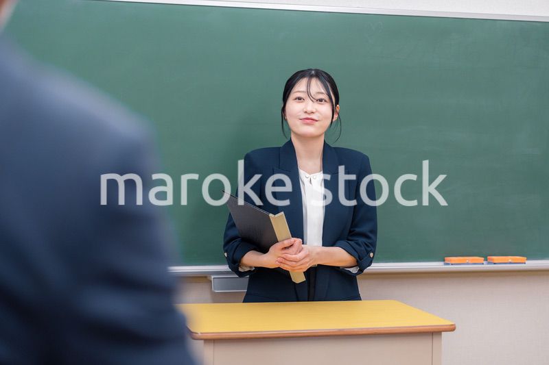 学校で教壇に立って授業をする若い女性教師