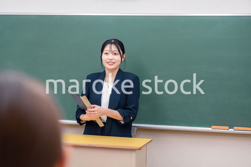 学校で教壇に立って授業をする若い女性教師