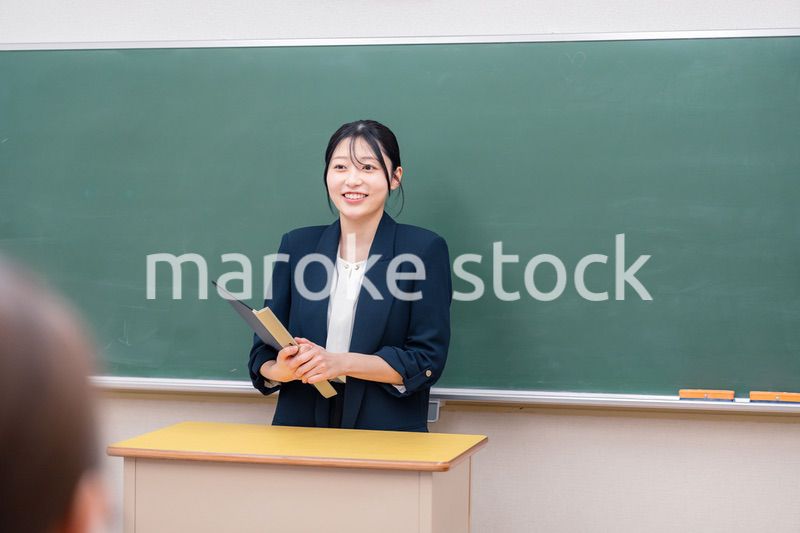 学校で教壇に立って授業をする若い女性教師