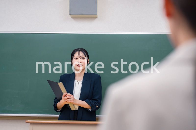 学校で教壇に立って授業をする若い女性教師