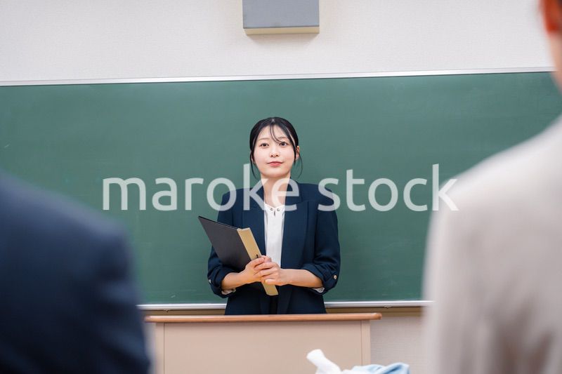 学校で教壇に立って授業をする若い女性教師
