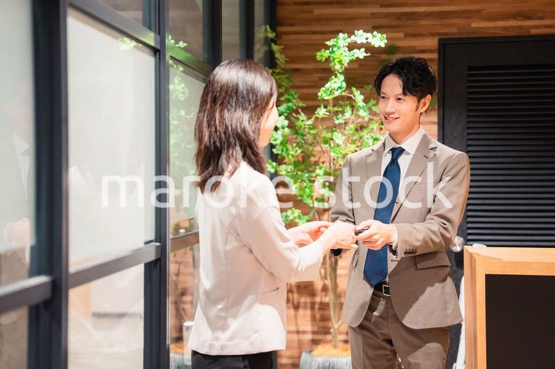 オフィスのエントランスで名刺交換をするビジネスパーソン