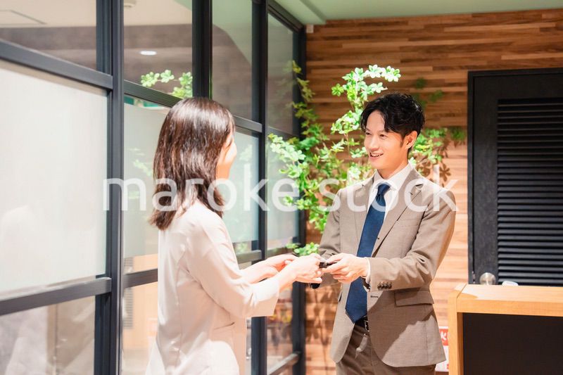 オフィスのエントランスで名刺交換をするビジネスパーソン