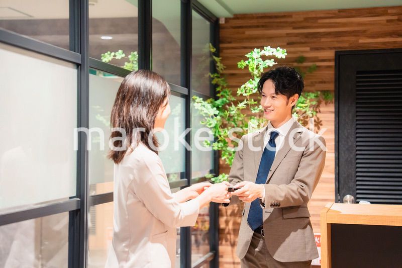 オフィスのエントランスで名刺交換をするビジネスパーソン