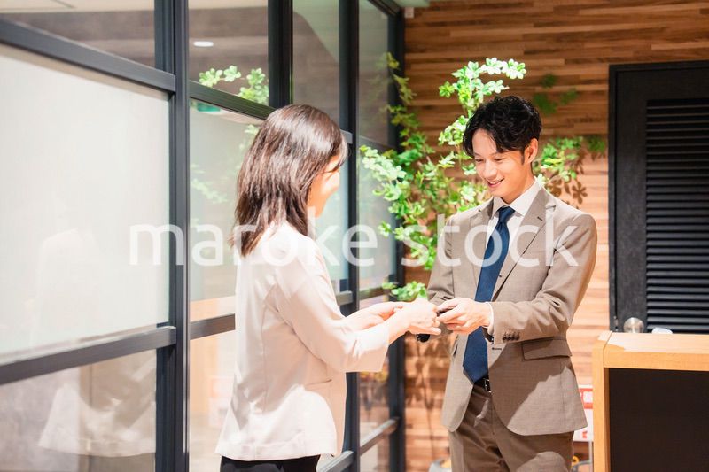 オフィスのエントランスで名刺交換をするビジネスパーソン