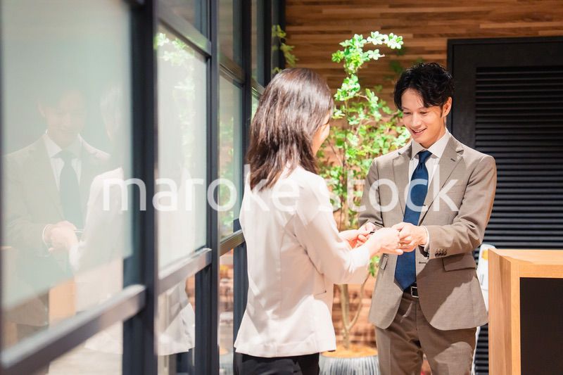 オフィスのエントランスで名刺交換をするビジネスパーソン