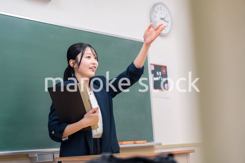 学校で教壇に立って授業をする若い女性教師