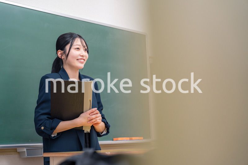 学校で教壇に立って授業をする若い女性教師