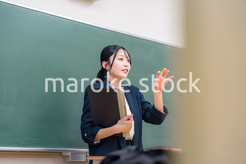 学校で教壇に立って授業をする若い女性教師