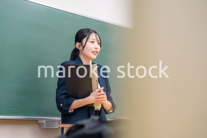 学校で教壇に立って授業をする若い女性教師