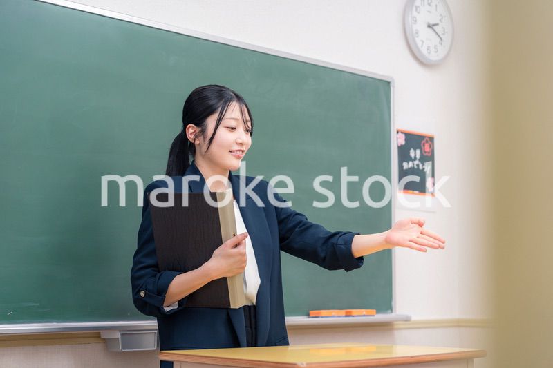学校で教壇に立って授業をする若い女性教師