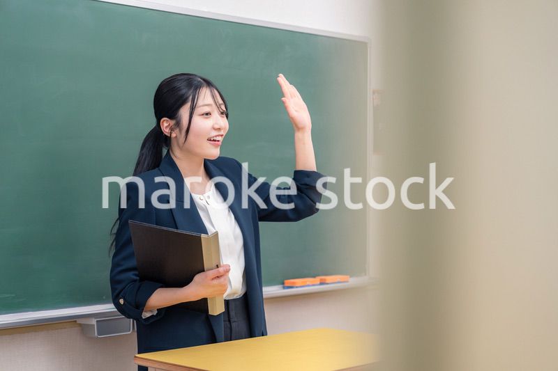 学校で教壇に立って授業をする若い女性教師