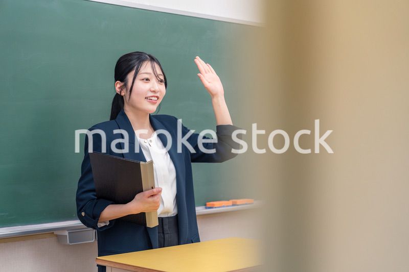 学校で教壇に立って授業をする若い女性教師
