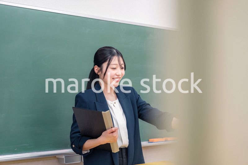 学校で教壇に立って授業をする若い女性教師