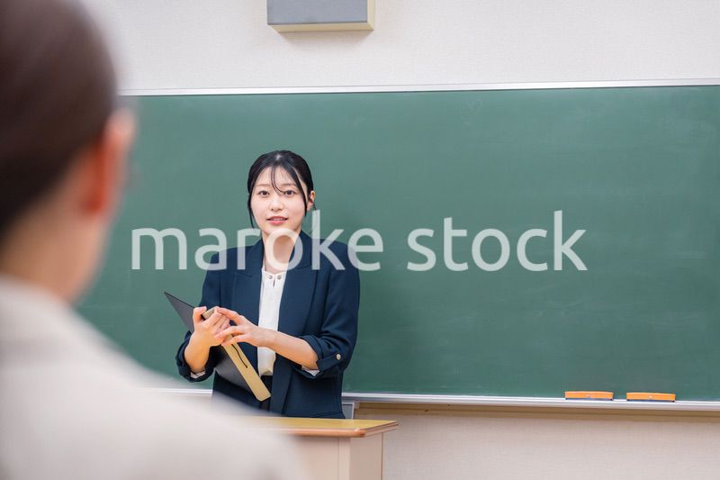 学校で教壇に立って授業をする若い女性教師