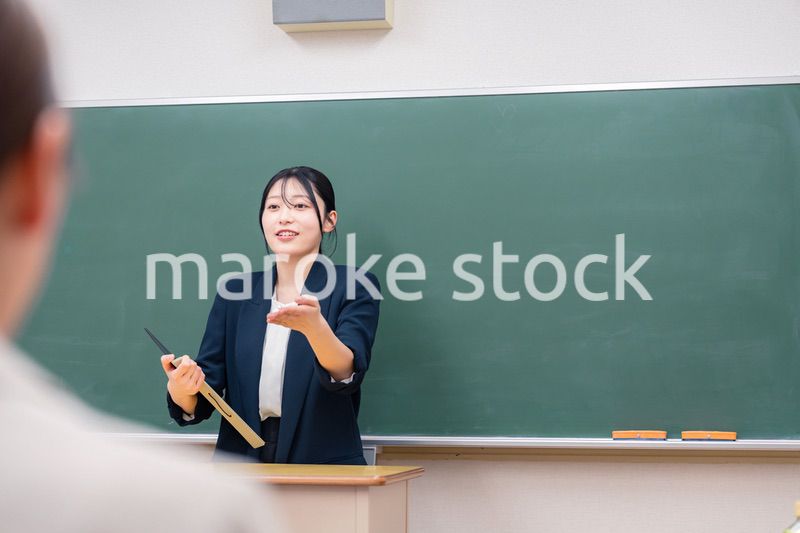 学校で教壇に立って授業をする若い女性教師