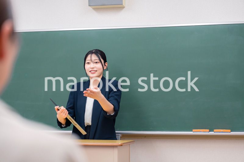 学校で教壇に立って授業をする若い女性教師