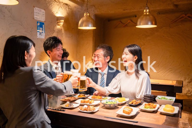 居酒屋で乾杯をする男女のビジネスパーソン