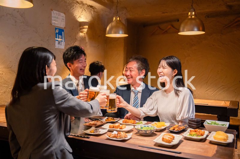 居酒屋で乾杯をする男女のビジネスパーソン