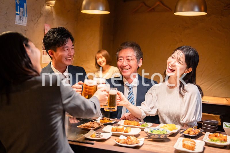 居酒屋で乾杯をする男女のビジネスパーソン