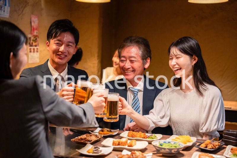 居酒屋で乾杯をする男女のビジネスパーソン