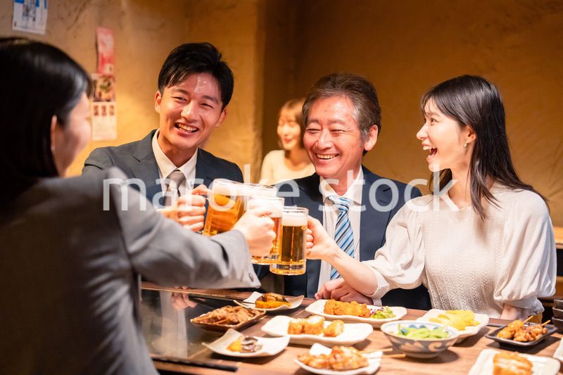 居酒屋で乾杯をする男女のビジネスパーソン
