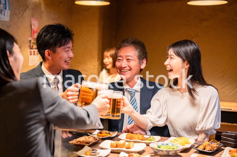 居酒屋で乾杯をする男女のビジネスパーソン