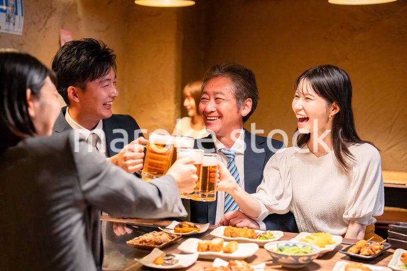 居酒屋で乾杯をする男女のビジネスパーソン
