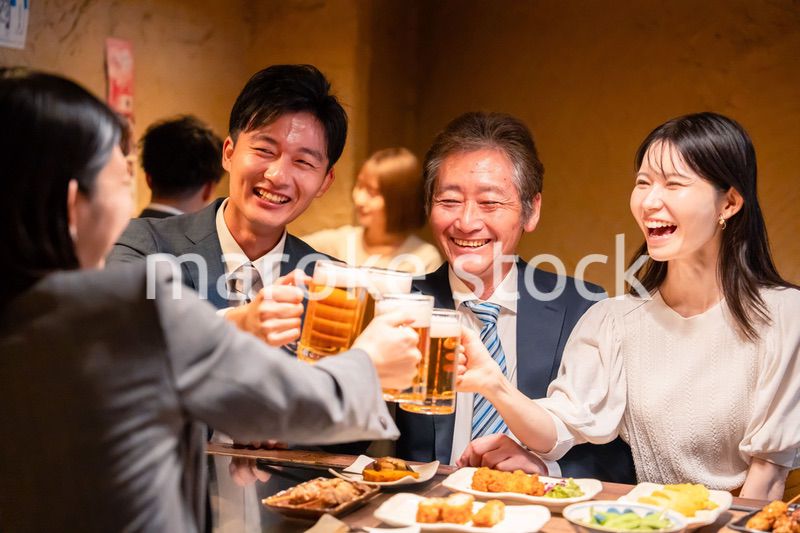居酒屋で乾杯をする男女のビジネスパーソン