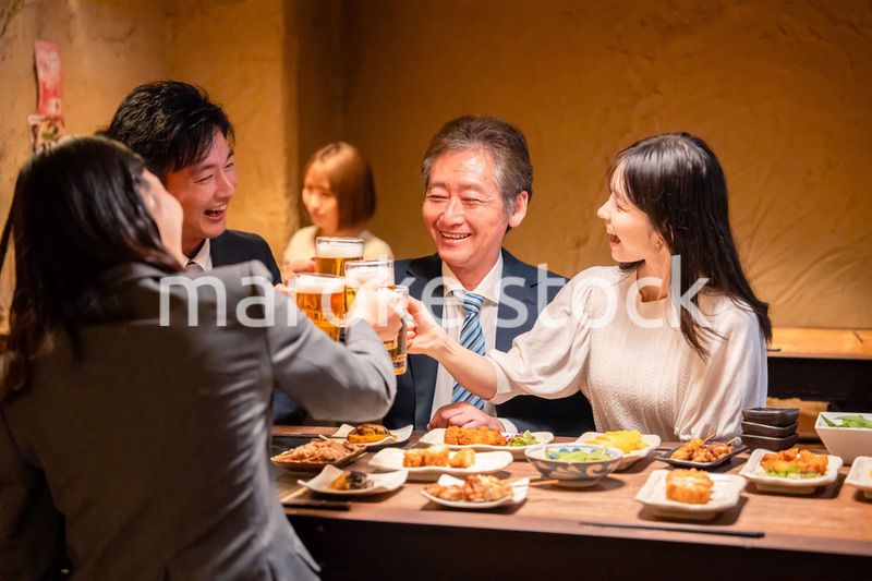 居酒屋で乾杯をする男女のビジネスパーソン