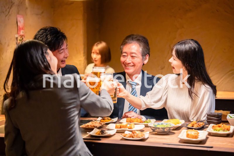 居酒屋で乾杯をする男女のビジネスパーソン