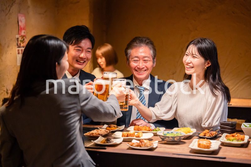 居酒屋で乾杯をする男女のビジネスパーソン