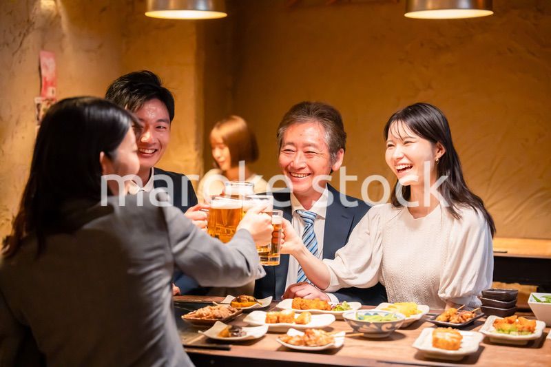 居酒屋で乾杯をする男女のビジネスパーソン