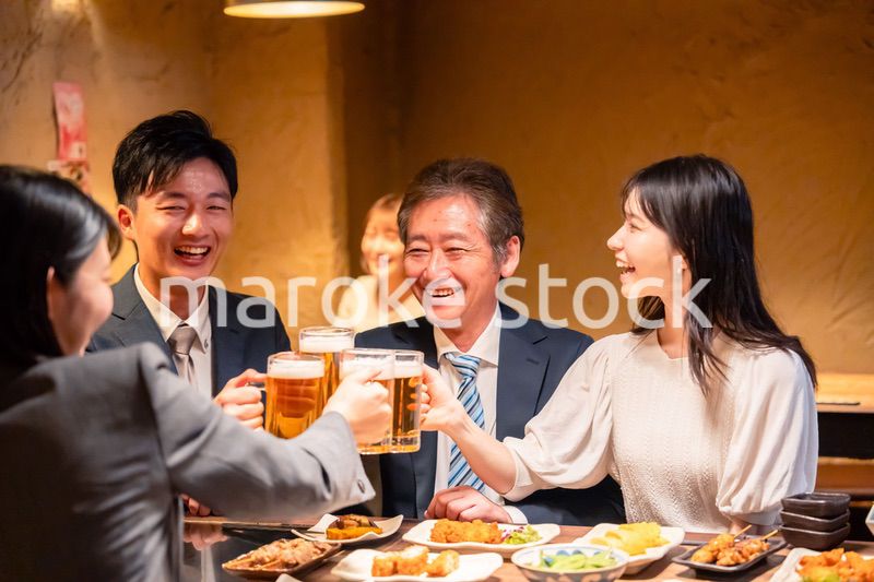 居酒屋で乾杯をする男女のビジネスパーソン