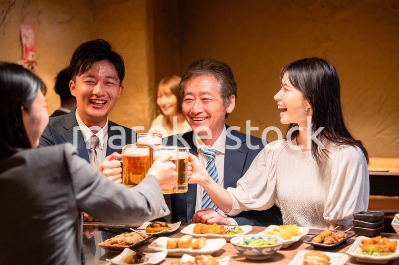 居酒屋で乾杯をする男女のビジネスパーソン