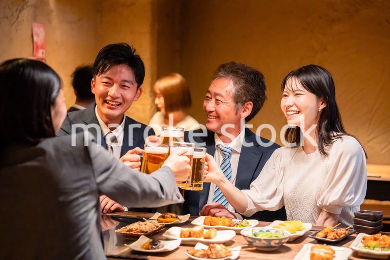 居酒屋で乾杯をする男女のビジネスパーソン