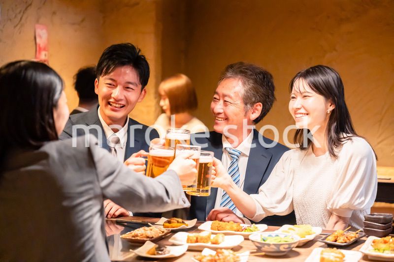居酒屋で乾杯をする男女のビジネスパーソン