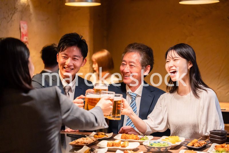 居酒屋で乾杯をする男女のビジネスパーソン