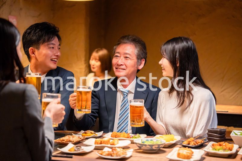 居酒屋で乾杯をする男女のビジネスパーソン