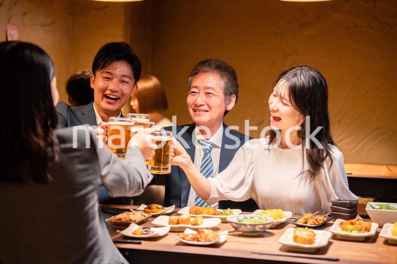 居酒屋で乾杯をする男女のビジネスパーソン