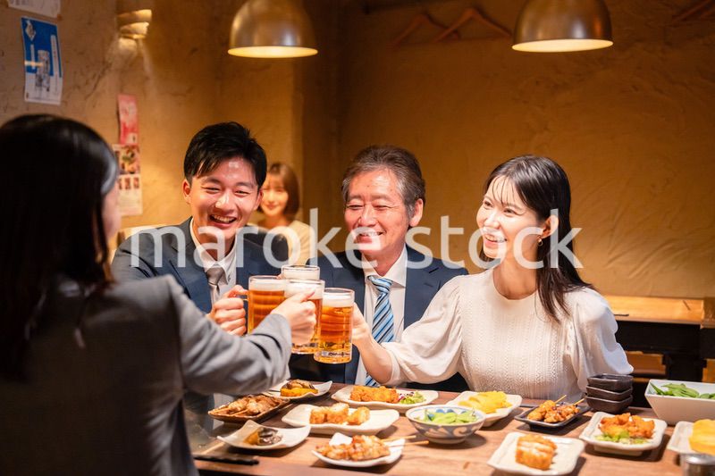 居酒屋で乾杯をする男女のビジネスパーソン
