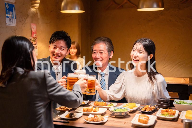 居酒屋で乾杯をする男女のビジネスパーソン
