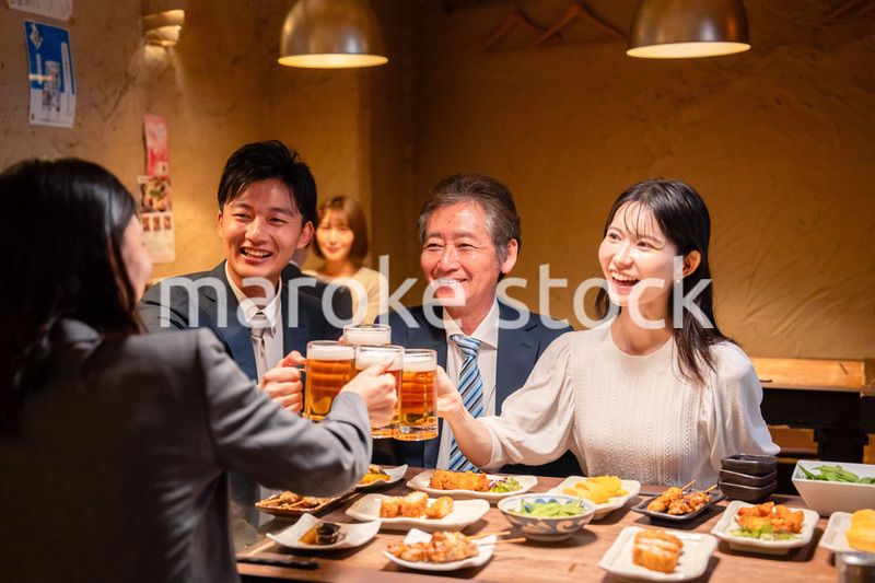 居酒屋で乾杯をする男女のビジネスパーソン