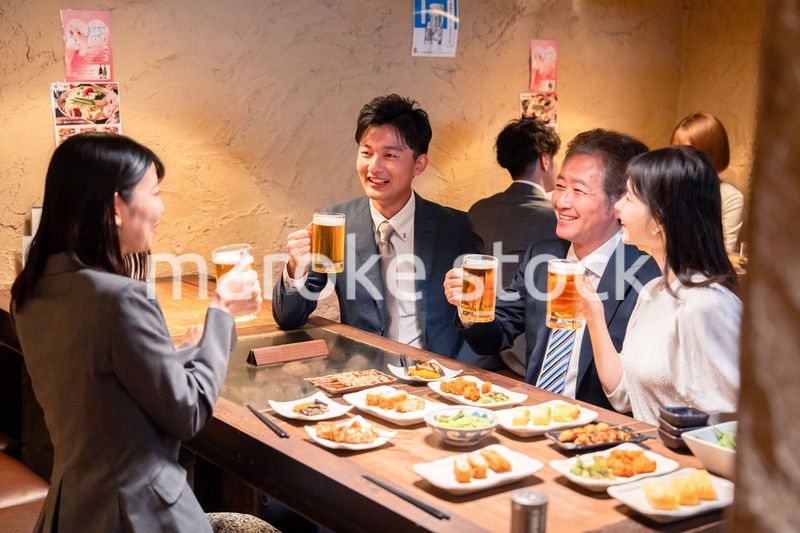 居酒屋で部署のお疲れ様会をするビジネスパーソン
