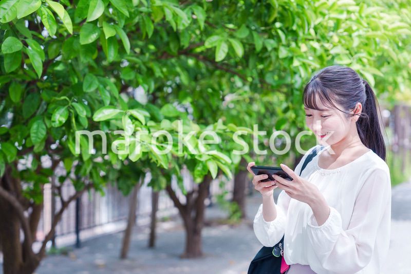 笑顔でスマホを見ながら歩く若い女性