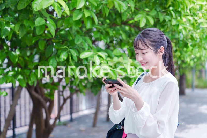笑顔でスマホを見ながら歩く若い女性