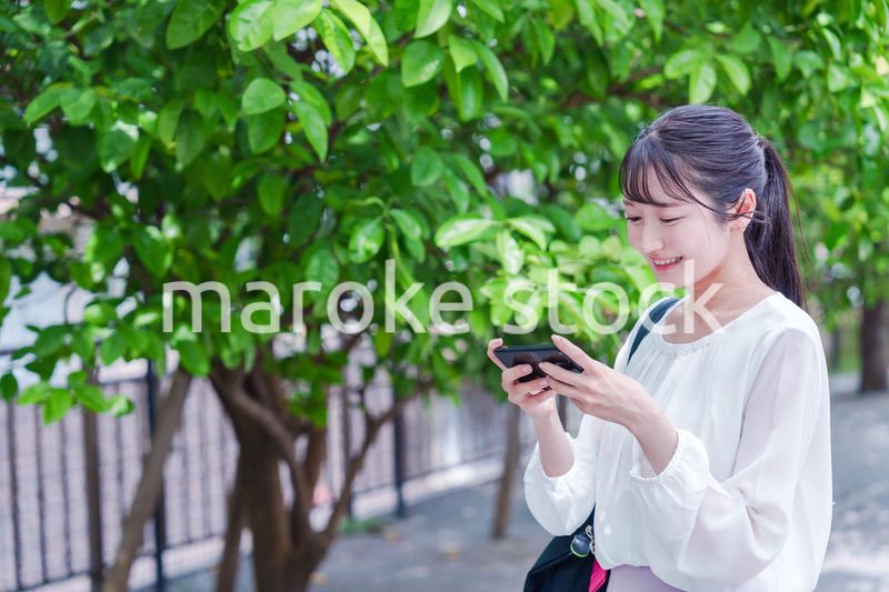 笑顔でスマホを見ながら歩く若い女性