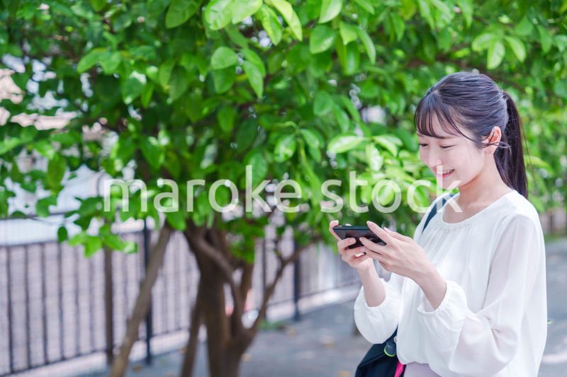 笑顔でスマホを見ながら歩く若い女性