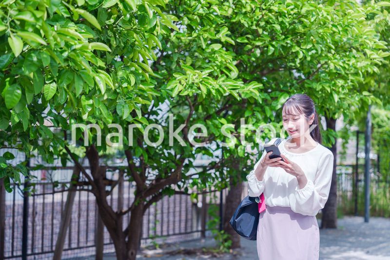 笑顔でスマホを見ながら歩く若い女性